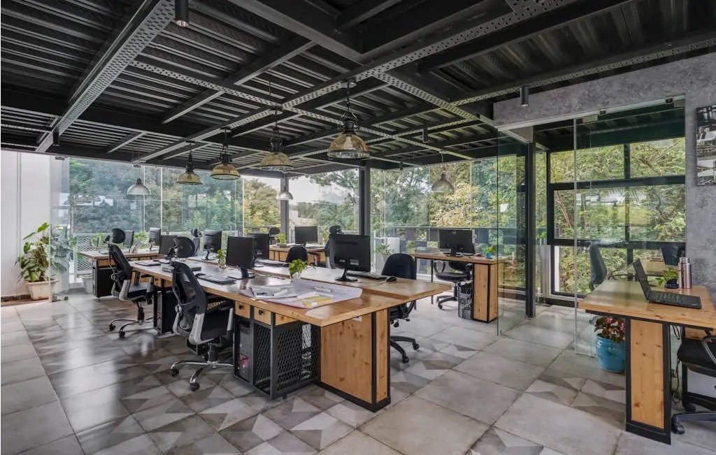 Open-plan office with timber workstations under an exposed steel ceiling